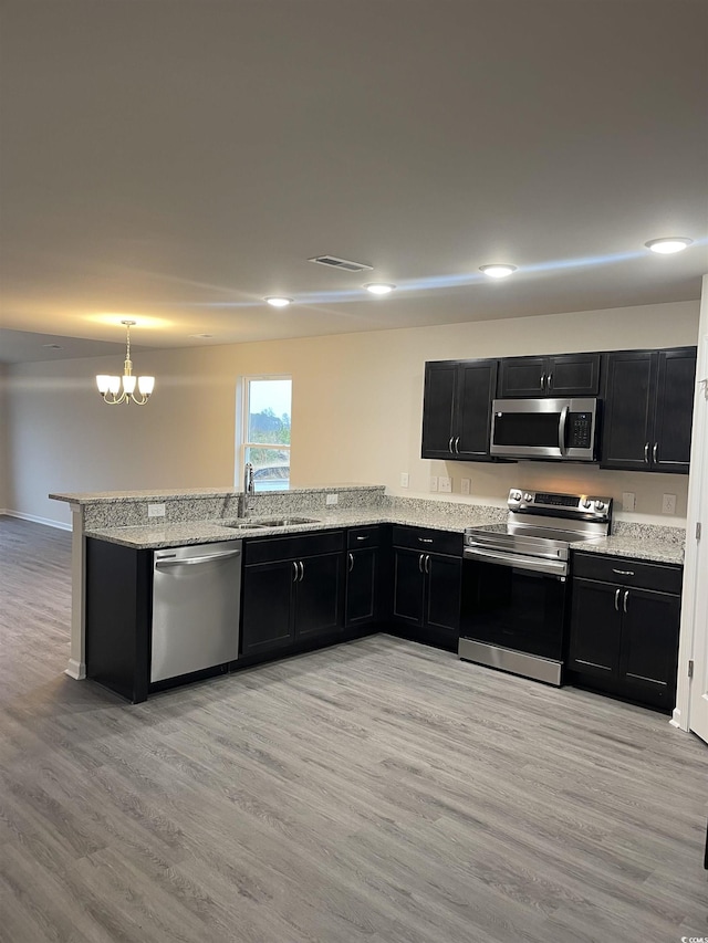 kitchen featuring sink, light wood-type flooring, a notable chandelier, kitchen peninsula, and stainless steel appliances