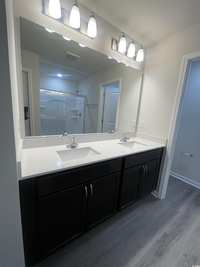 bathroom with hardwood / wood-style floors, vanity, and walk in shower