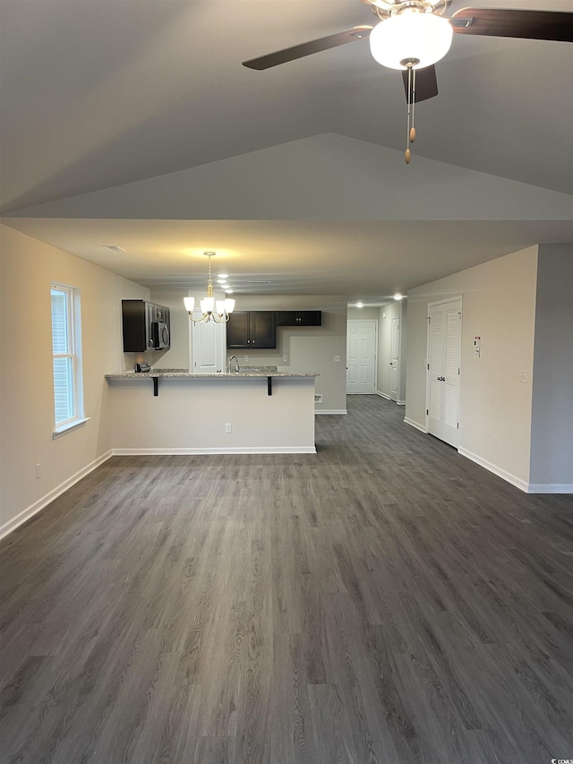 unfurnished living room with ceiling fan with notable chandelier, lofted ceiling, and dark wood-type flooring