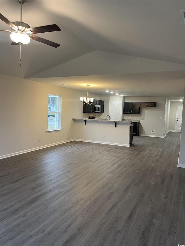 unfurnished living room with lofted ceiling, ceiling fan with notable chandelier, and dark wood-type flooring