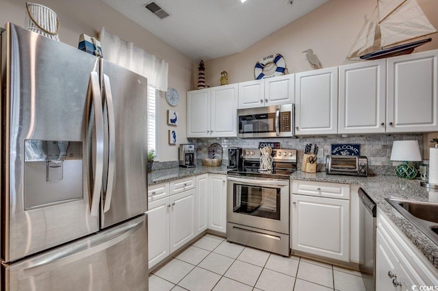 kitchen featuring white cabinets, appliances with stainless steel finishes, light tile patterned floors, and light stone countertops