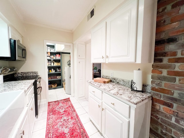 kitchen featuring brick wall, white cabinetry, range with two ovens, light tile patterned floors, and crown molding