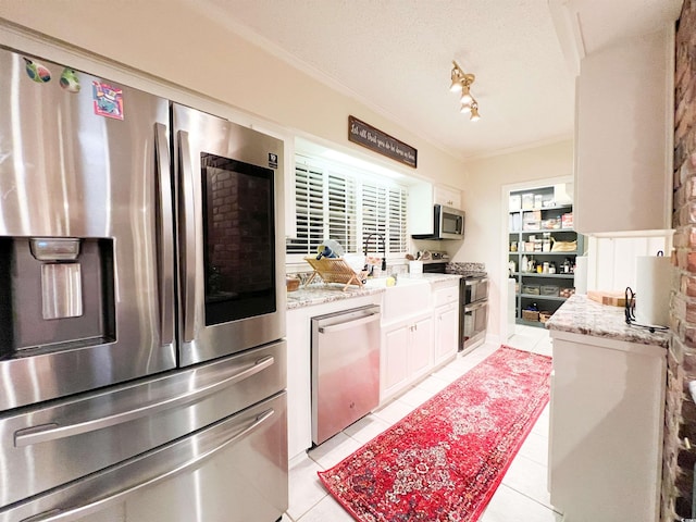 kitchen with light tile patterned floors, crown molding, appliances with stainless steel finishes, a textured ceiling, and white cabinets