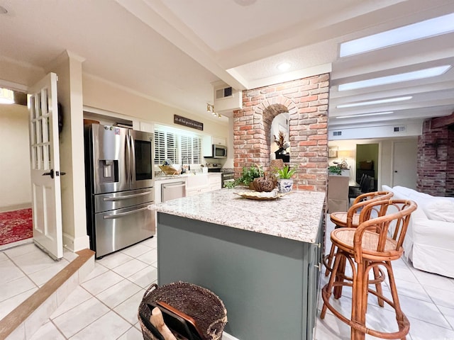 kitchen featuring light stone counters, light tile patterned floors, gray cabinets, and appliances with stainless steel finishes