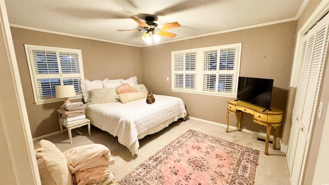 carpeted bedroom featuring ceiling fan, ornamental molding, a closet, and a textured ceiling