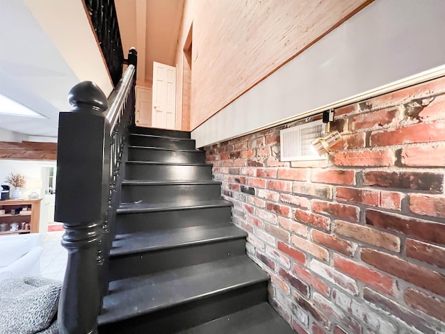 staircase featuring tile patterned flooring and brick wall