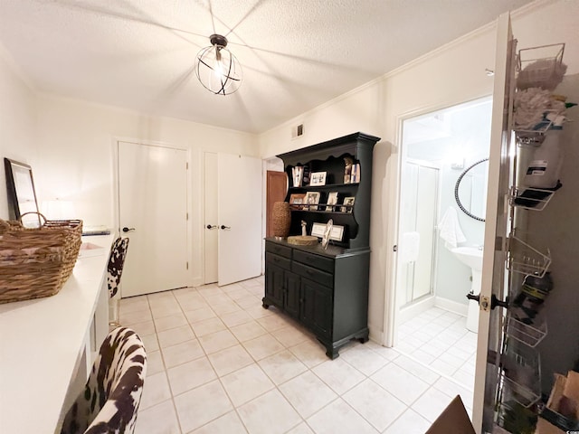 kitchen with crown molding, a textured ceiling, and light tile patterned floors