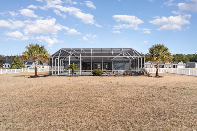 rear view of property with a lawn and glass enclosure