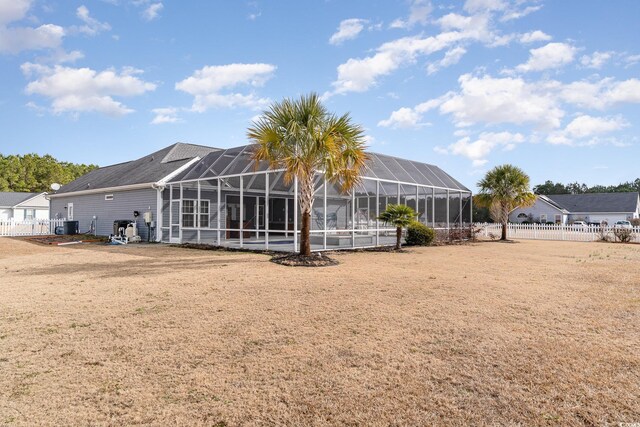 back of property featuring central AC, glass enclosure, and a lawn