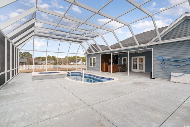 view of pool with glass enclosure, french doors, exterior bar, a patio area, and an in ground hot tub