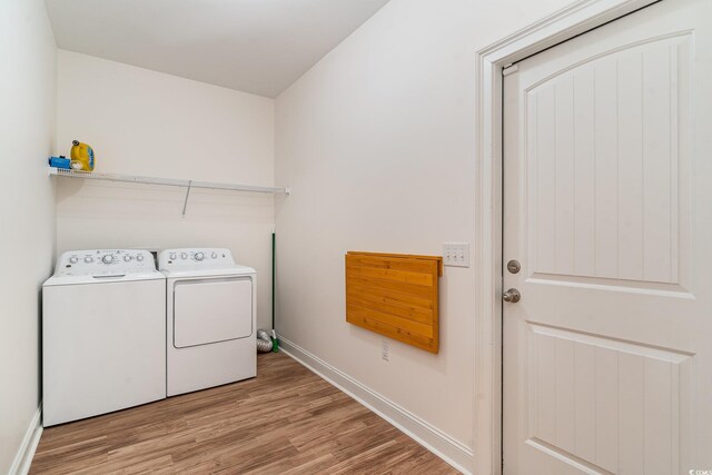 washroom featuring washing machine and dryer and light hardwood / wood-style flooring