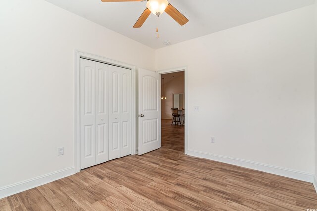 unfurnished bedroom with light wood-type flooring, a closet, and ceiling fan