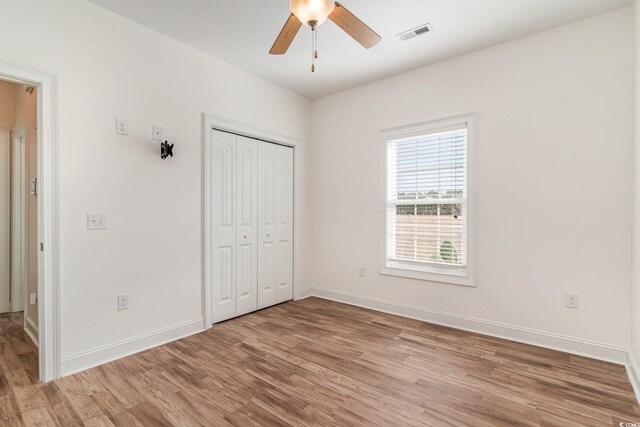 unfurnished bedroom featuring ceiling fan, light hardwood / wood-style flooring, and a closet