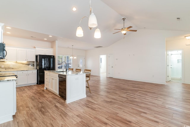 kitchen with backsplash, a kitchen island with sink, black appliances, white cabinets, and light hardwood / wood-style floors