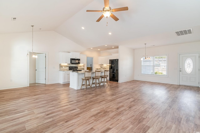 unfurnished living room featuring ceiling fan with notable chandelier, light hardwood / wood-style floors, sink, and high vaulted ceiling