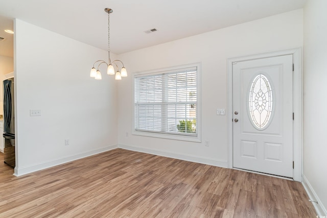 foyer with light wood-type flooring and a notable chandelier