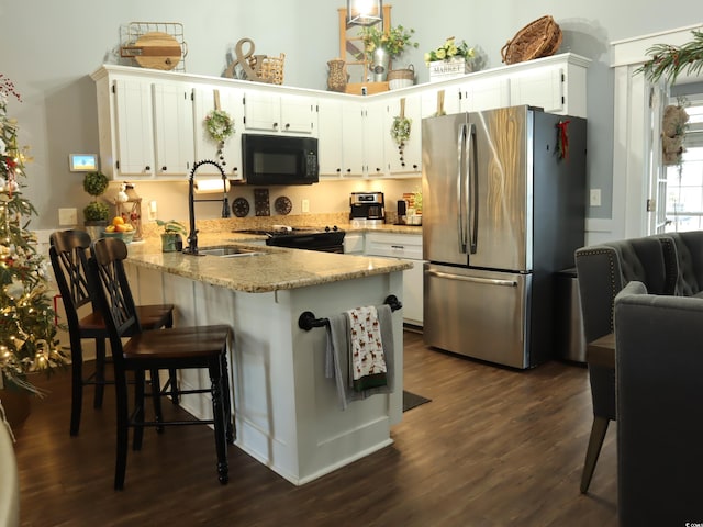 kitchen featuring kitchen peninsula, dark hardwood / wood-style flooring, sink, white cabinetry, and stainless steel refrigerator