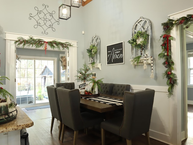 dining area with wood-type flooring and a towering ceiling