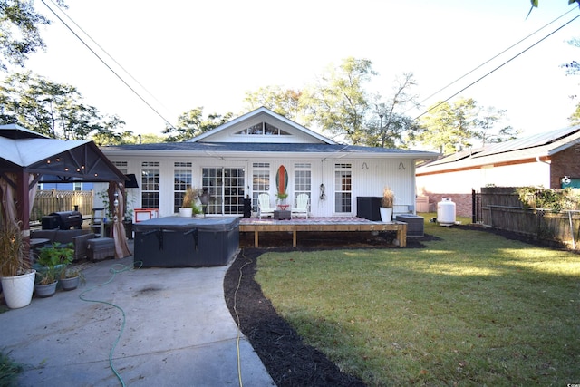 rear view of house featuring a gazebo, a yard, a patio, and a hot tub