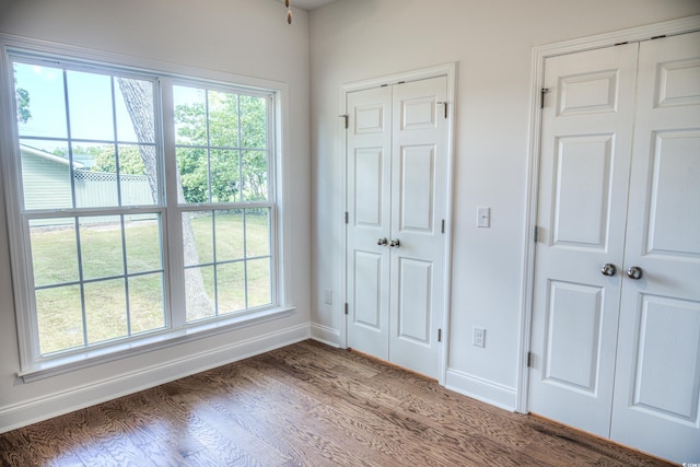 unfurnished bedroom with dark wood-type flooring and multiple closets