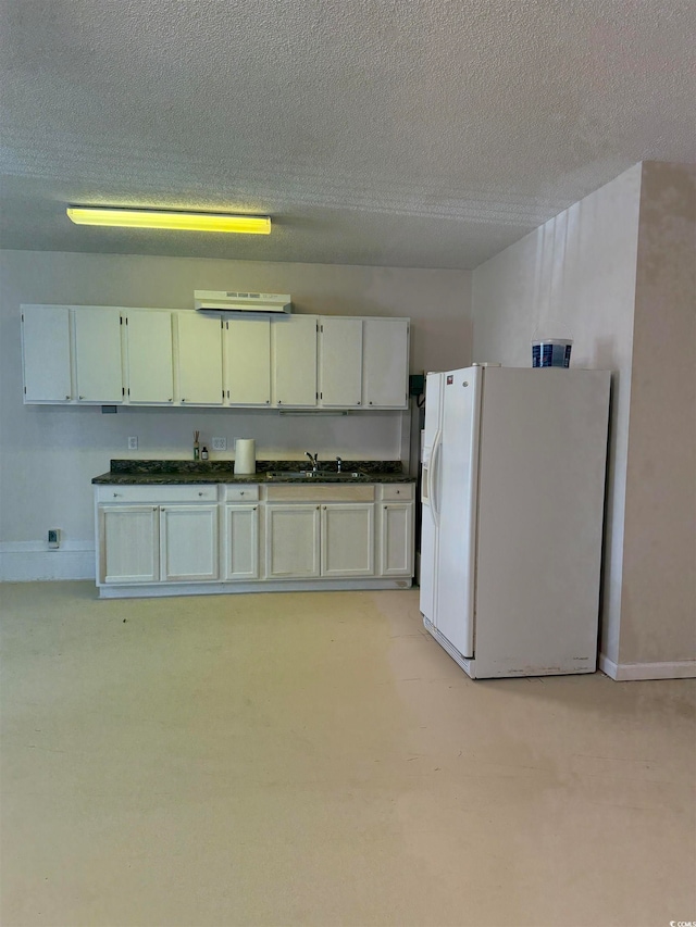 basement featuring white refrigerator with ice dispenser, a textured ceiling, and sink