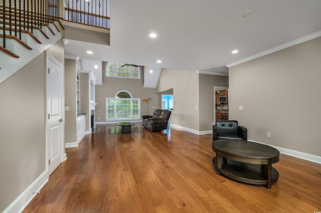 living area with crown molding, light hardwood / wood-style flooring, and a high ceiling