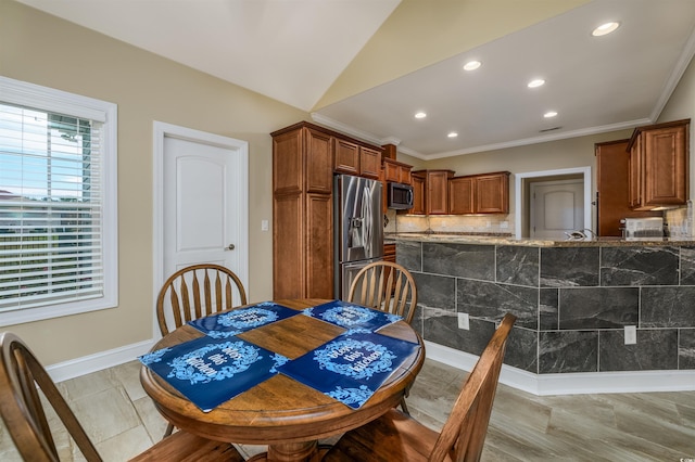 dining space featuring crown molding and vaulted ceiling