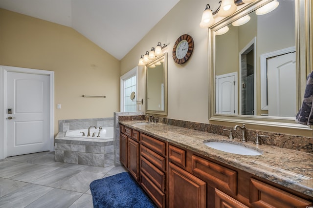 bathroom featuring vaulted ceiling, a relaxing tiled tub, and vanity