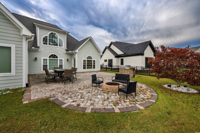 back house at dusk with a lawn, exterior kitchen, and a patio