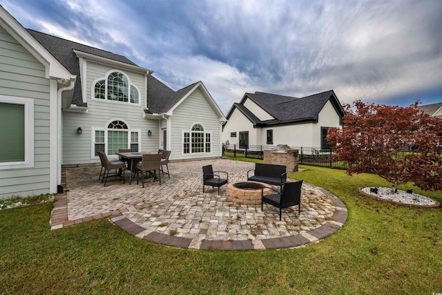 rear view of property featuring a fire pit, a lawn, and a patio area