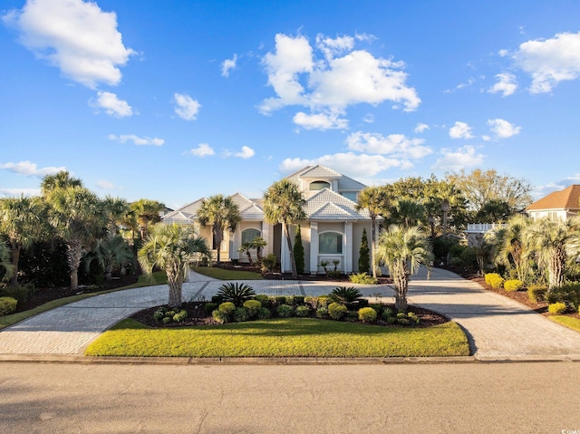 view of front of home featuring a tile roof, a front yard, decorative driveway, and stucco siding