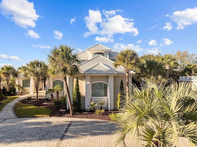 mediterranean / spanish-style house featuring a tile roof, decorative driveway, and stucco siding