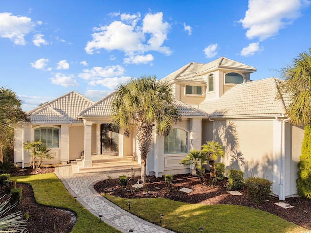 mediterranean / spanish home with a tiled roof and stucco siding