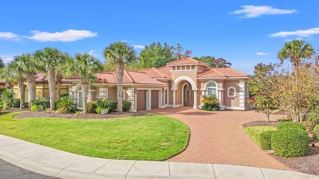 mediterranean / spanish-style home featuring a front lawn and a garage