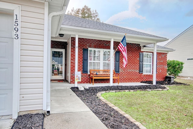 entrance to property with covered porch and a yard