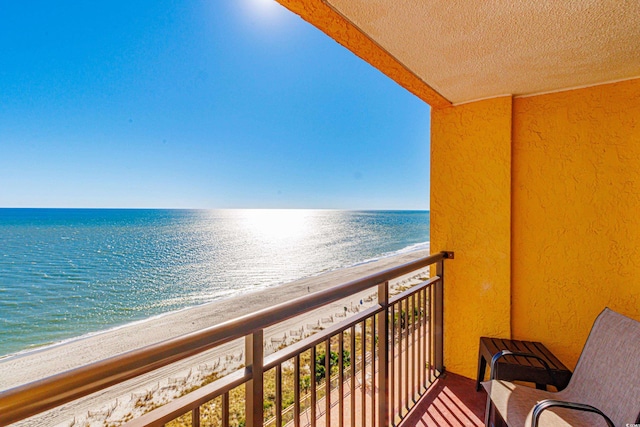 balcony featuring a view of the beach and a water view