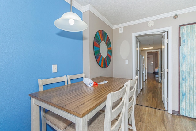 dining room featuring hardwood / wood-style floors, a textured ceiling, and crown molding