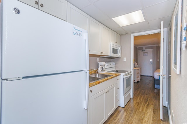 kitchen with sink, light hardwood / wood-style flooring, white appliances, a paneled ceiling, and white cabinets