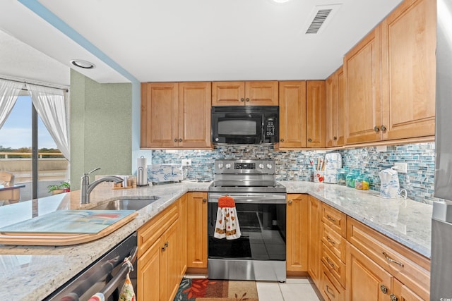 kitchen featuring backsplash, sink, light stone countertops, light tile patterned floors, and stainless steel appliances