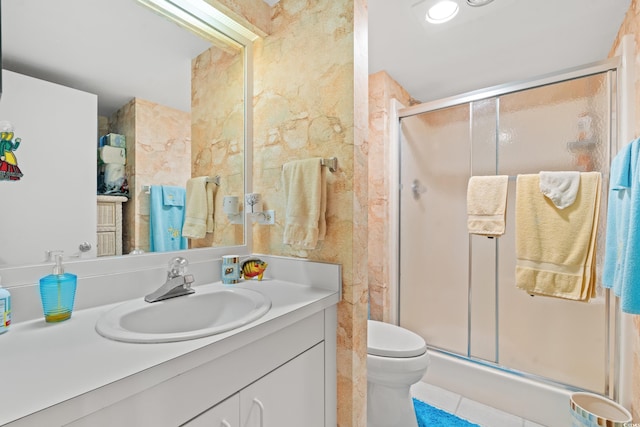 bathroom with tile patterned flooring, vanity, a shower with shower door, and toilet