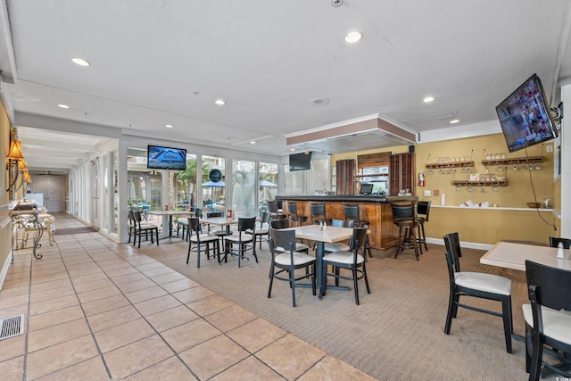 dining area featuring bar, light tile patterned flooring, and a textured ceiling