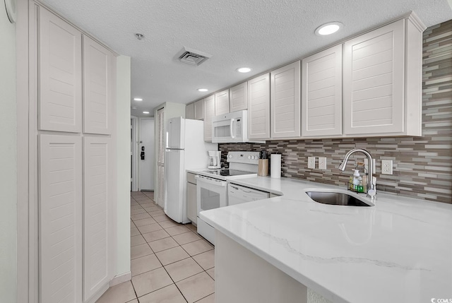 kitchen featuring backsplash, white appliances, sink, light tile patterned floors, and white cabinets