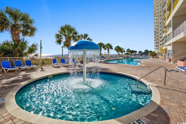 view of swimming pool with pool water feature and a patio