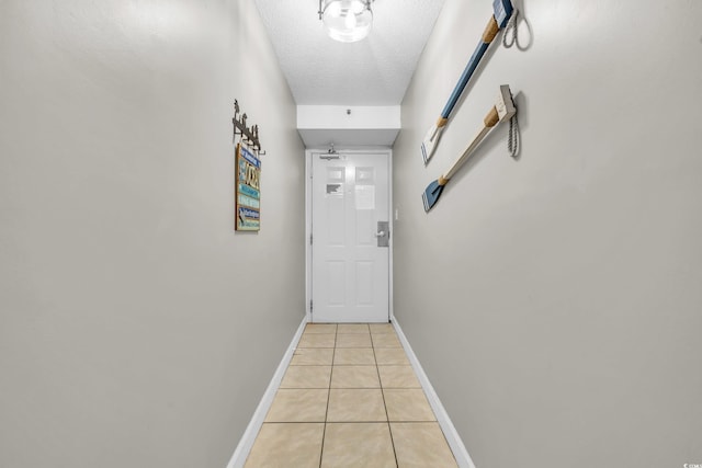 hall featuring light tile patterned floors and a textured ceiling