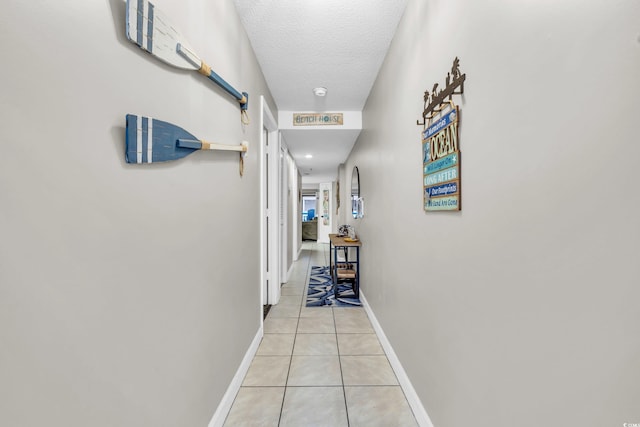 hall featuring light tile patterned floors and a textured ceiling