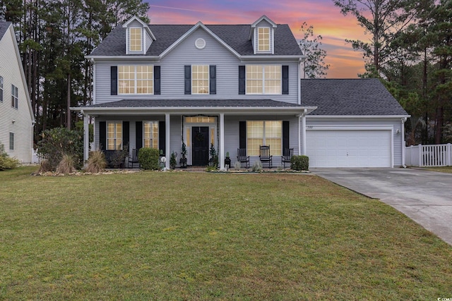 view of front of home featuring a yard, covered porch, and a garage