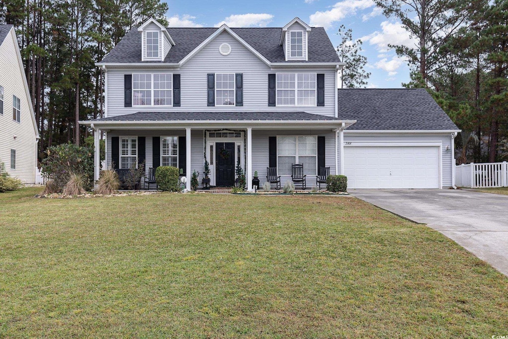 view of front of property featuring a front yard, a garage, and covered porch