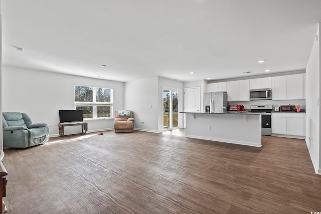 kitchen featuring a breakfast bar area, an island with sink, white cabinetry, wood-type flooring, and stainless steel appliances