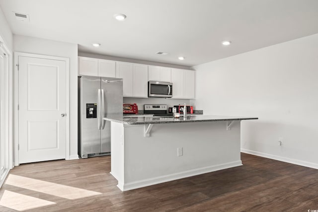 kitchen with hardwood / wood-style floors, a center island with sink, white cabinets, and stainless steel appliances