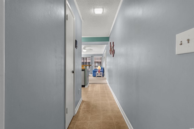 hallway featuring light tile patterned floors, a textured ceiling, and ornamental molding